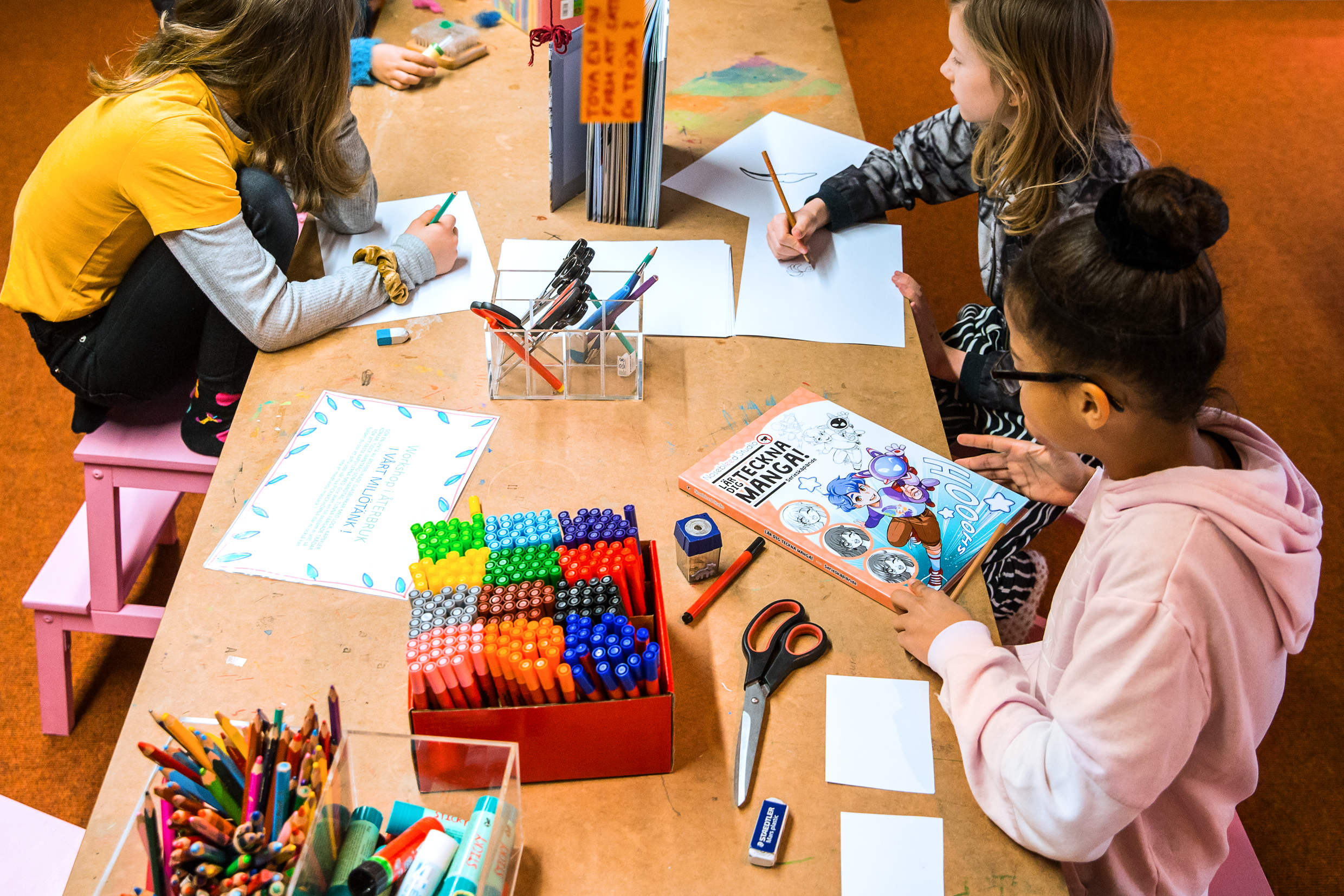 Tre barn vid ett ritbord