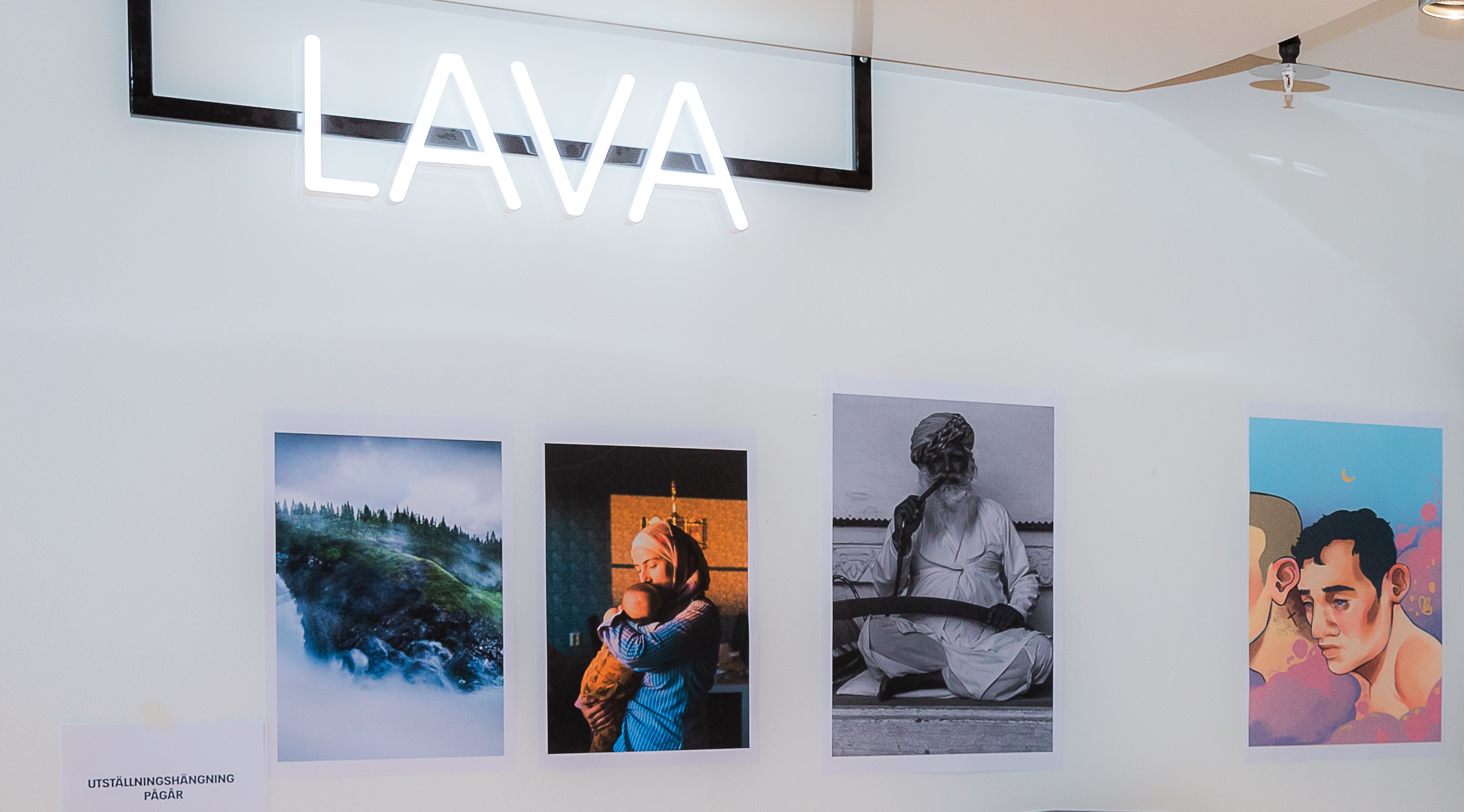 Tavlor uppsatta på en vägg samt en skylt där det står Lava. 