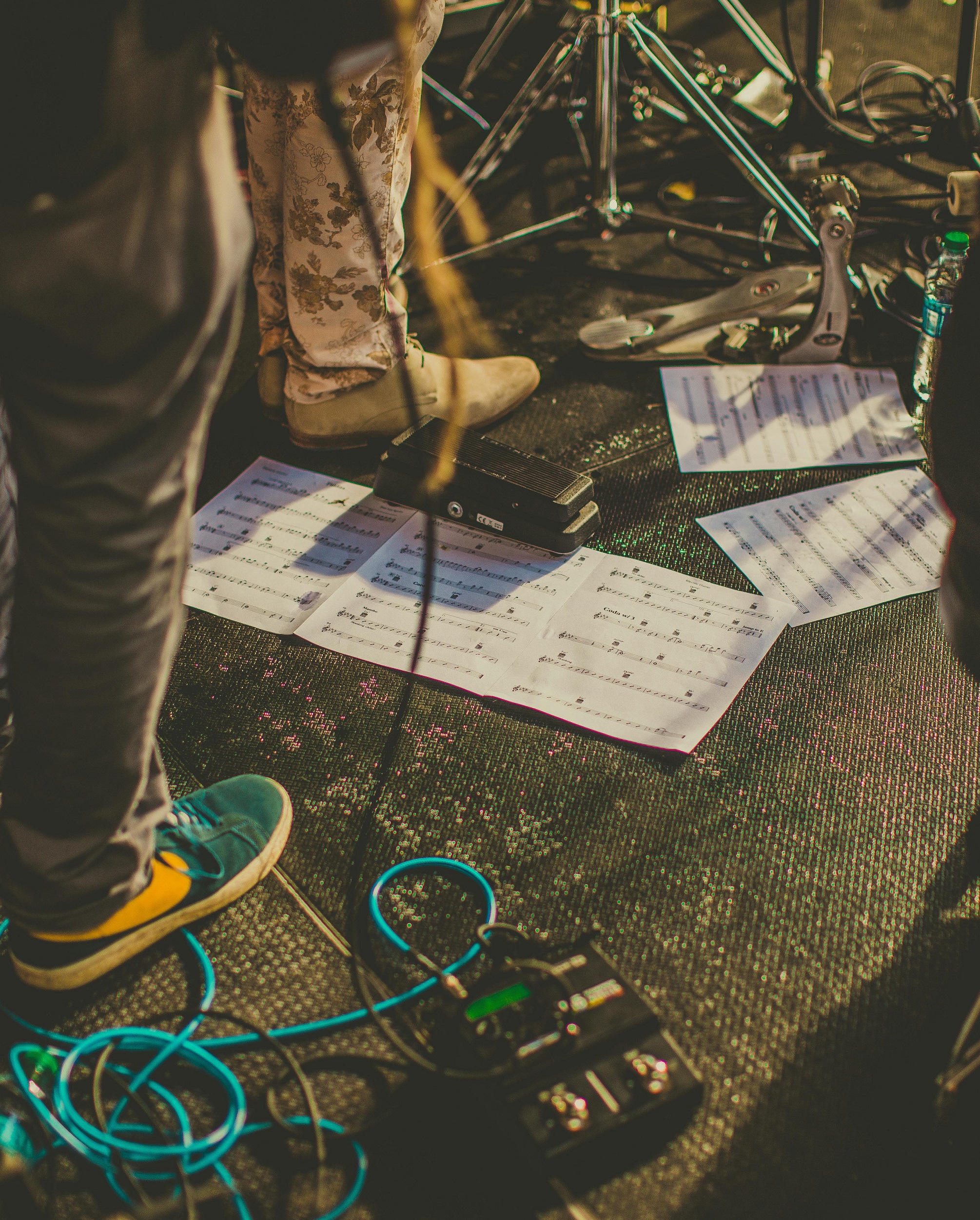 Ett scengolv fullt av kablar, papper med noter, ställningar för olika instrument med mera. 
