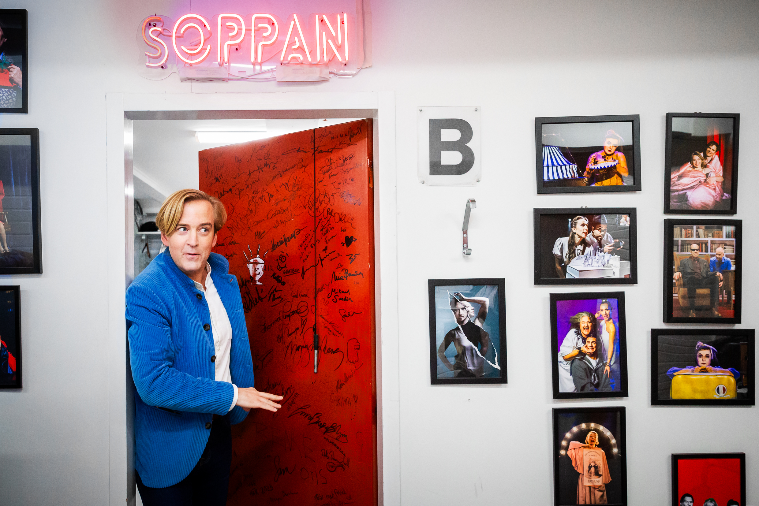 Andreas T Olsson tittar ut genom dörren till Soppteaterns loge. På väggarna hänger fotografier från Soppteaterns olika produktioner.