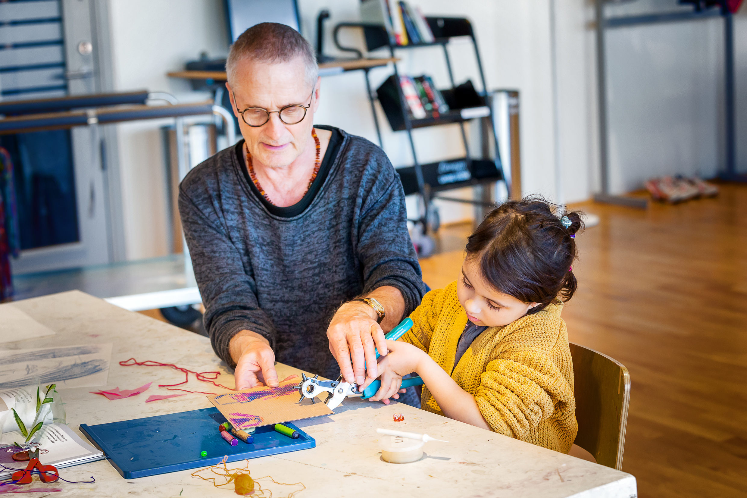 Ett barn och en vuxen sitter vid ett bord och skapar konst av kartong