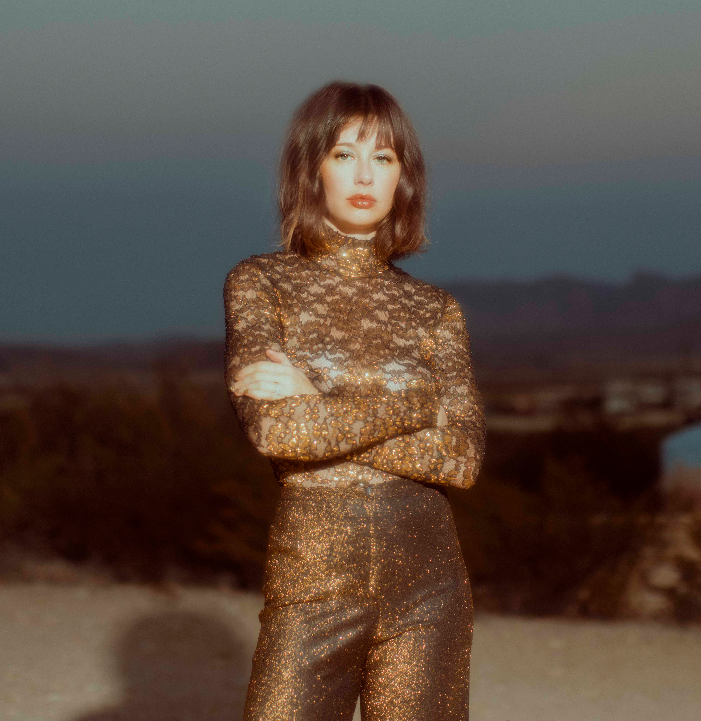 En kvinna i guldklädsel fotad i naturen