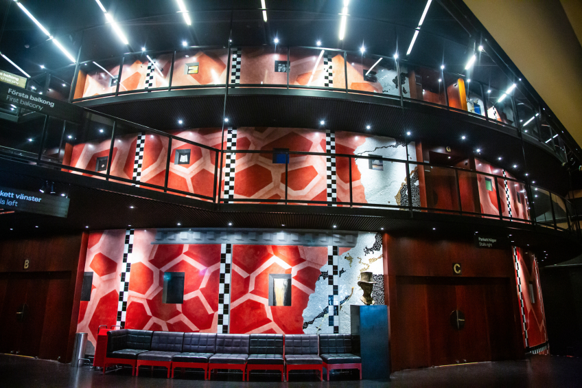 Stora scenens foajé, med rött mosaik-liknande konstverk på väggarna