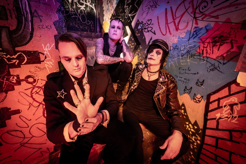 Tre personer poserar i rosa ljus