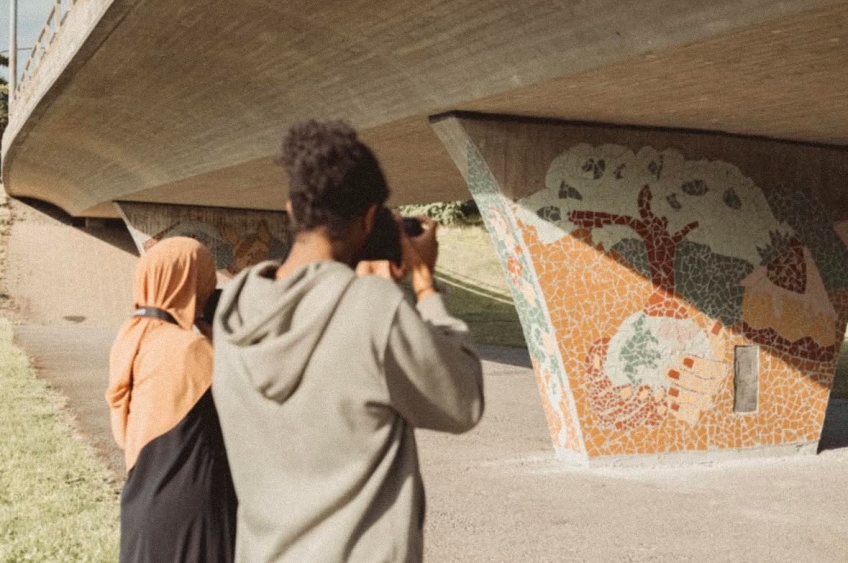 två ungdomar fotograferar under en bro