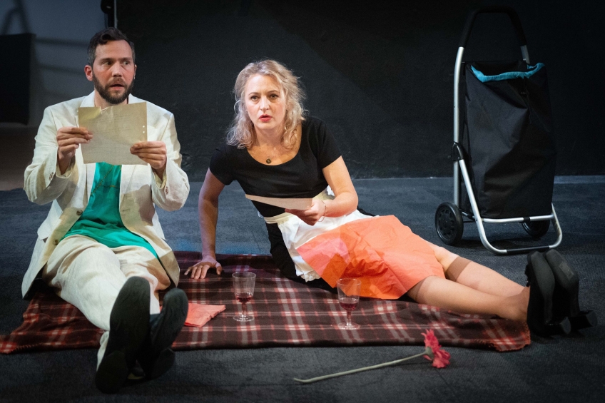 Två personer på en picknickfilt som läser från papper