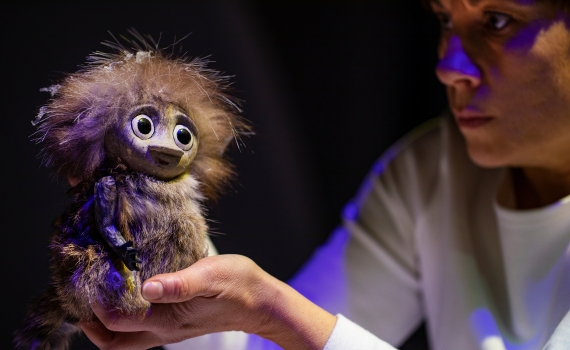 En dockskådespelare håller en docka i handen i föreställningen Granen.