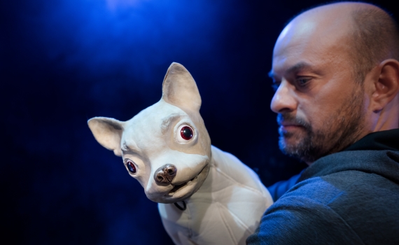 En man håller i en docka som ser ut som en hund. 