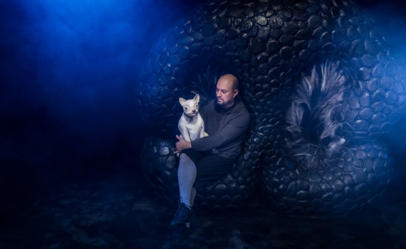 En man håller i en docka som ser ut som en hund. 