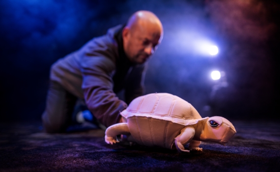 En man håller i en docka som ser ut som en sköldpadda. 