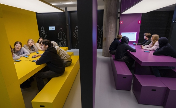 Ungdomar samlade kring ett gult bord och ett lila bord. 