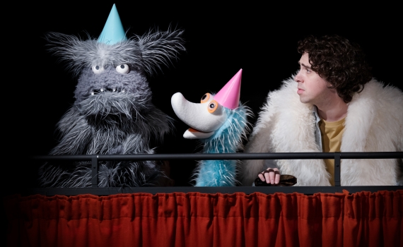 Två lurviga dockor med partyhattar och en människa klädd i vit päls. 