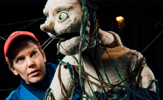 En dockskådespelare håller i en docka. 