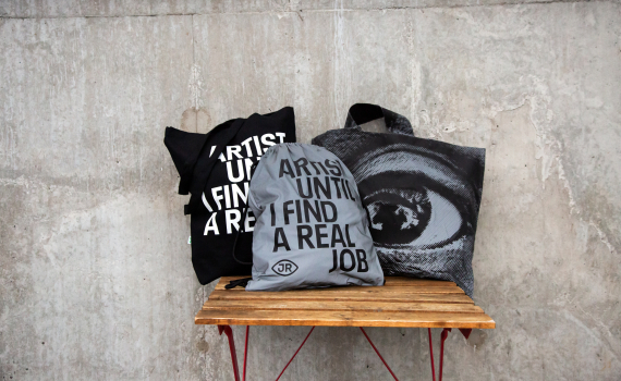 "Samling av JR-inspirerade väskor med budskapet 'Artist Until I Find A Real Job'. Snygga och praktiska för konstälskare på språng."