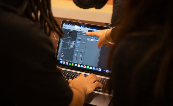 Två personer sitter och redigerar musik på en dator