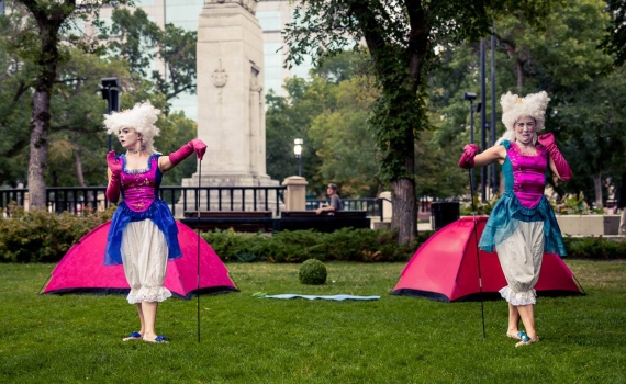 Två 1700-talsklädda drottningar framför varsitt tält