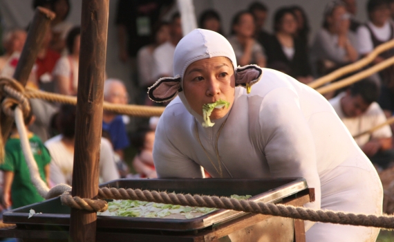 En artist utklädd till får som äter sallad