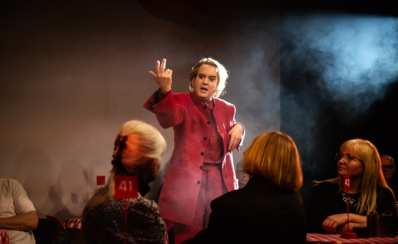 Andreas T Olsson som Dante i ett rum fullt av publik