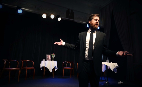 En man i svart kostym och svart slips under en minnesstund.