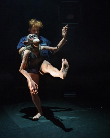 En man håller i en stor docka som ser ut som en apa. 