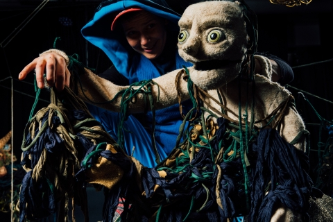 En dockskådespelare håller i en docka. 