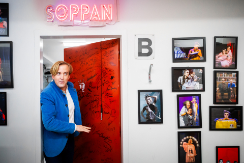 Andreas T Olsson tittar ut genom dörren till Soppteaterns loge. På väggarna hänger fotografier från Soppteaterns olika produktioner.