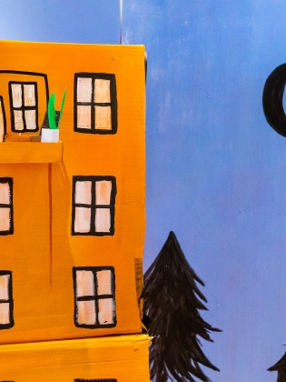 Ett hus i miniatyr med blå himmel och en måne i bakgrunden. 