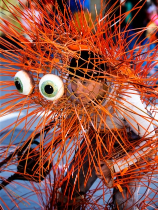 En docka med spretiga röda taggar och stora runda ögon. 