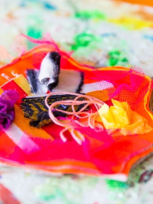 Handarbete av tygbitar, trådar och annat material i olika färger. 