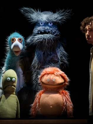 Fyra lurviga dockor och två människor tillsammans på scen. 