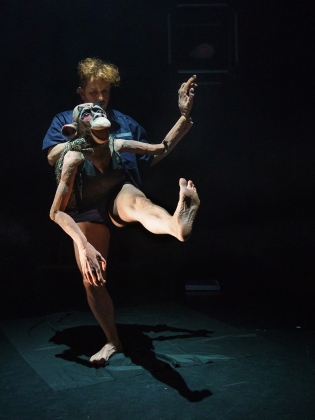 En man håller i en stor docka som ser ut som en apa. 