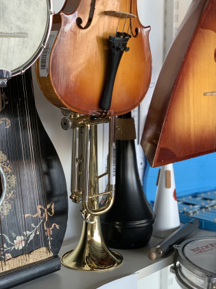 En hylla med olika instrument, trumpet, gitarr, banjo med flera. 
