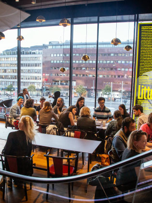 En grupp människor med olika bakgrunder samtalar runt ett bord på ett språkcafé.