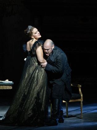 Två operasångare uppträder på en mörk scen.