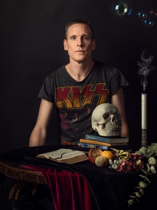 Kalle Haglund vid ett bord med böcker, en dödskalle och ett ljus