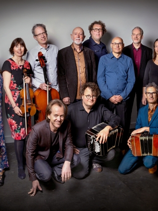 En stor samling musiker poserar med sina instrument