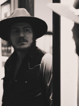 En man i hatt tittar i en spegel