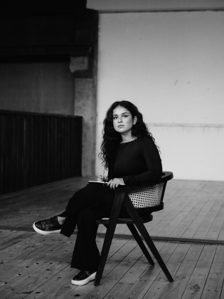 Sara Nazari sitter på en stol i ett tomt rum med en bok i knät