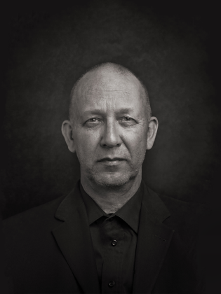 En man i svart kostym fotad i svartvitt