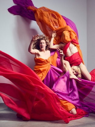 Det blåser och tre kvinnor trasslar in sig i färgglada tyger.