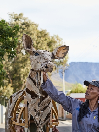 En dockspelare som håller i docka i naturlig storlek föreställandes en antilop