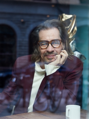 En man i glasögon innanför ett fönster