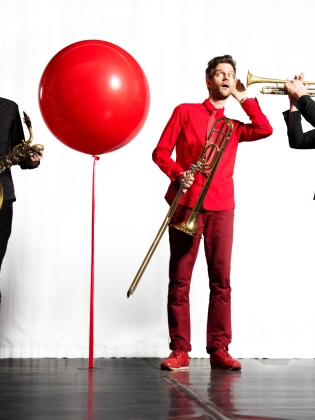 Tre blåsmusiker och en röd ballong