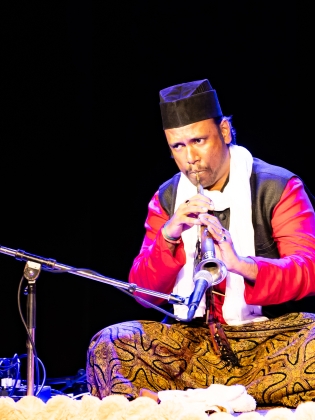 Bilden föreställer en man som sitter ner och spelar instrument