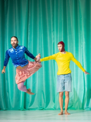 Två dansare i färgglada kläder som utför en koreografi