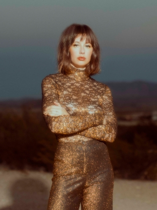 En kvinna i guldklädsel fotad i naturen