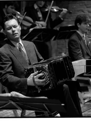 En man spelar dragspel på en scen.