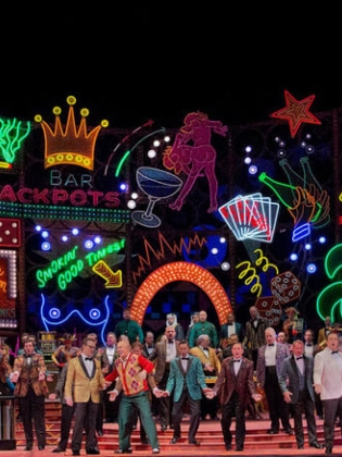 En grupp operasångare uppträder på en neonfylld scen.