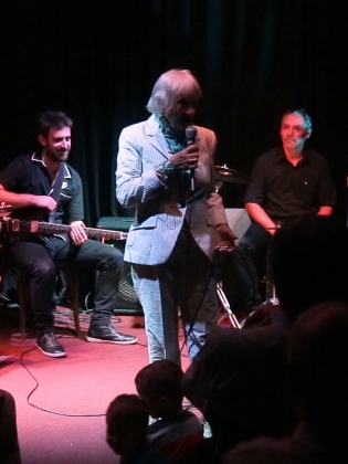 En kvinna sjunger på en scen omgiven av musiker.