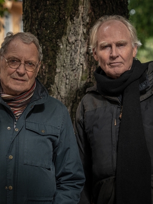 Foto på två män framför ett träd